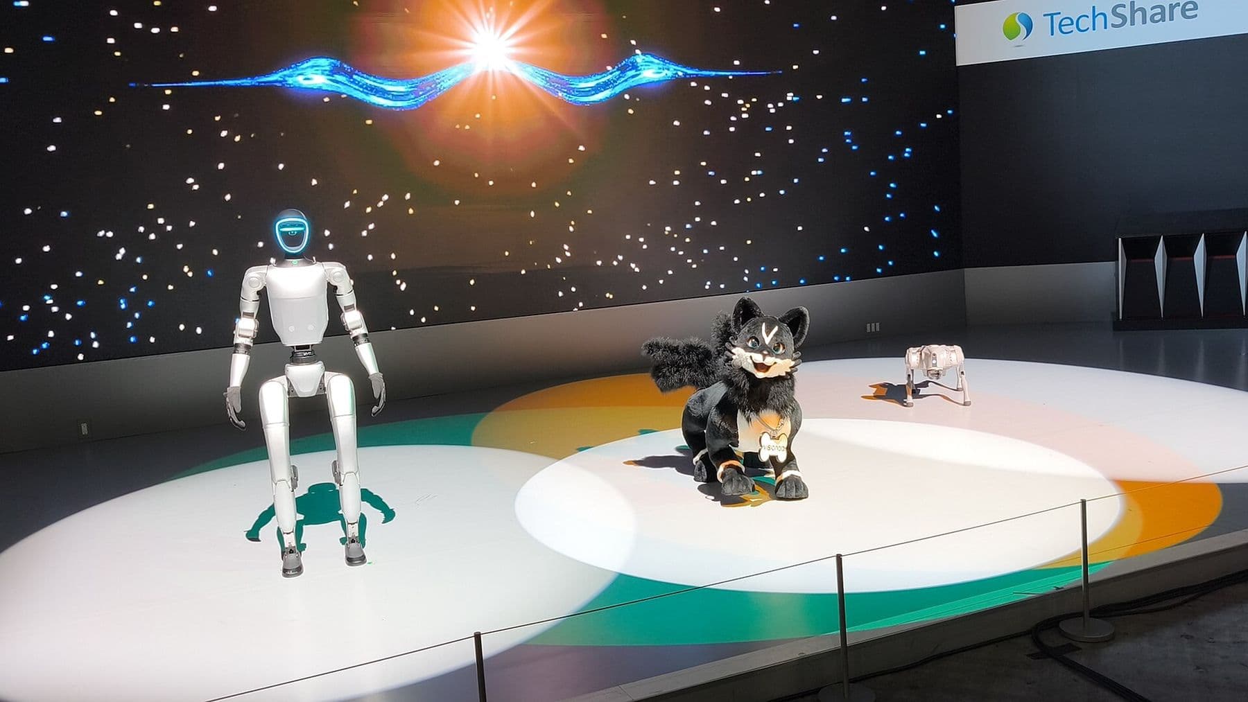 Unitree G1 humanoid robot on stage beside a robot fox and a robot dog