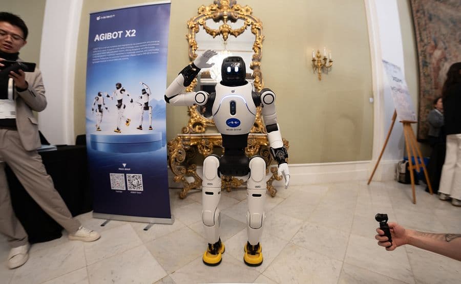 AgiBot X2 humanoid robot waving at an exhibition stand